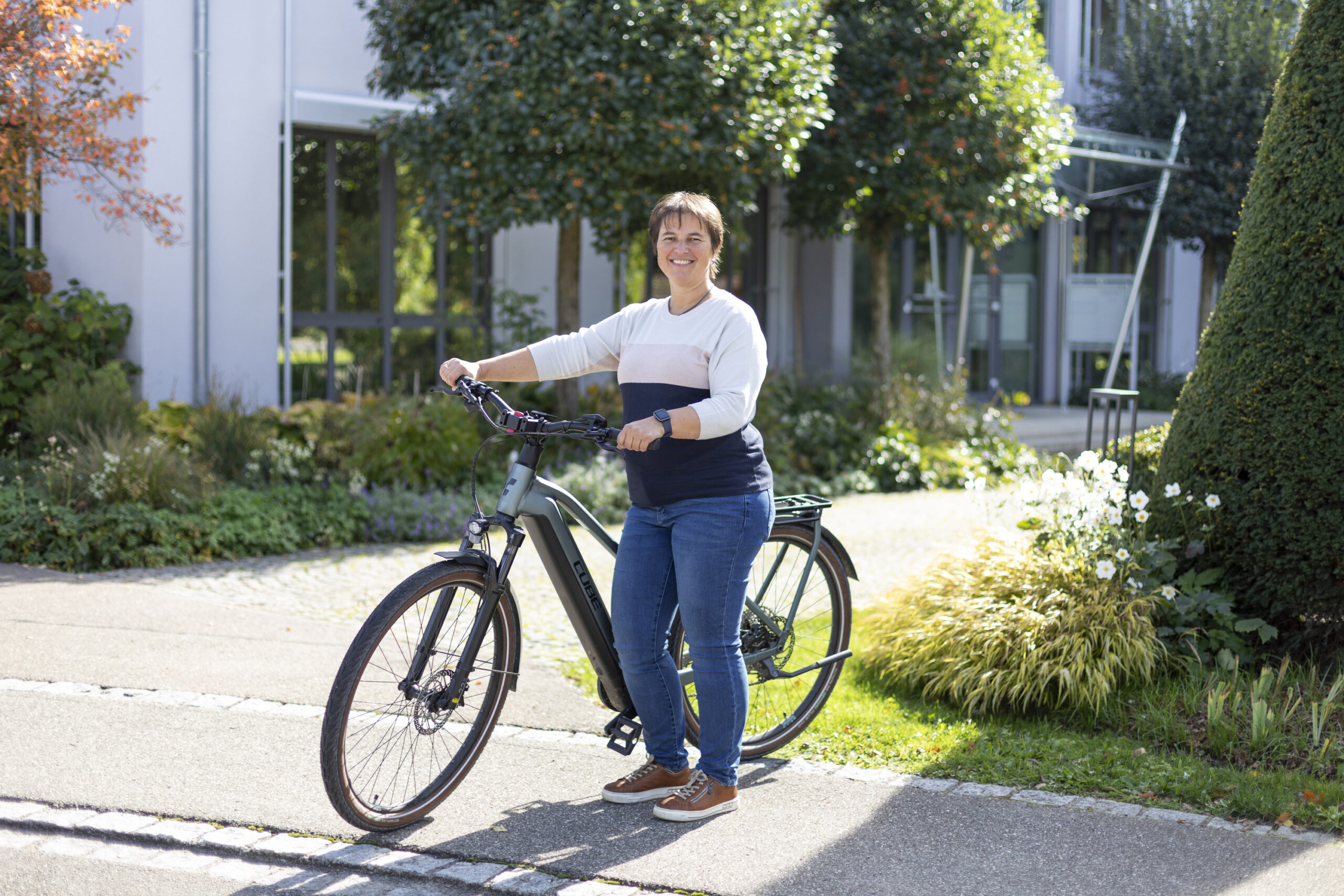 Renate Frei, Mitarbeiterin bei SCHUSTER engineering mit ihrem E-Bike vor dem Firmensitz.